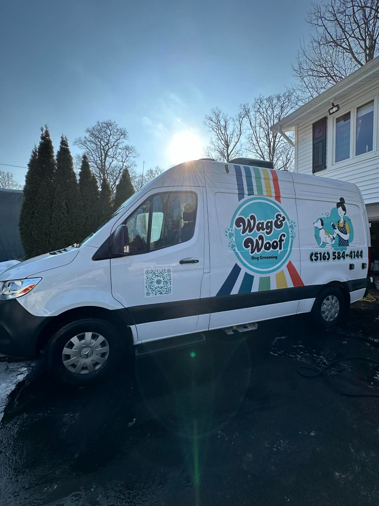 Side view of the Wag & Woof mobile dog grooming van with branding, parked in a driveway